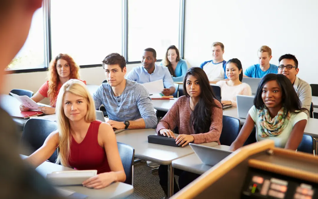 A class of students at their desks, listening to a lecture.