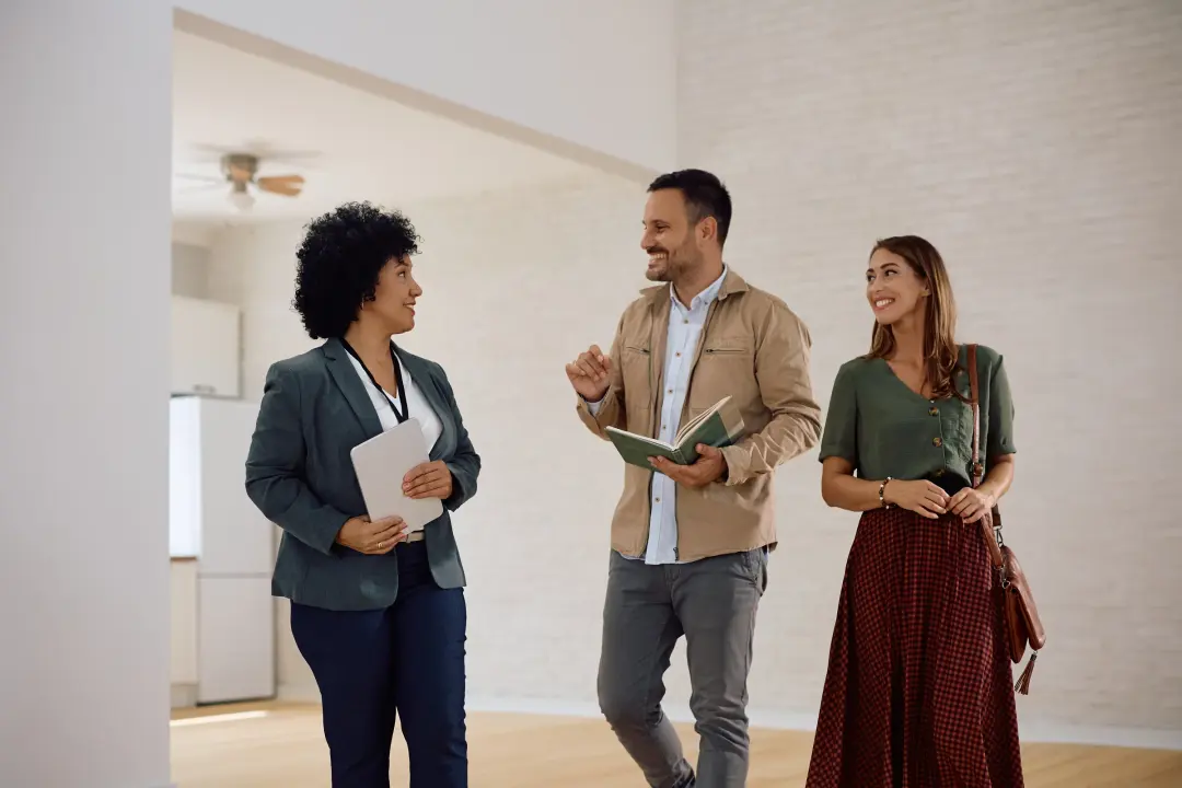 An estate agent showing a couple around an empty apartment.
