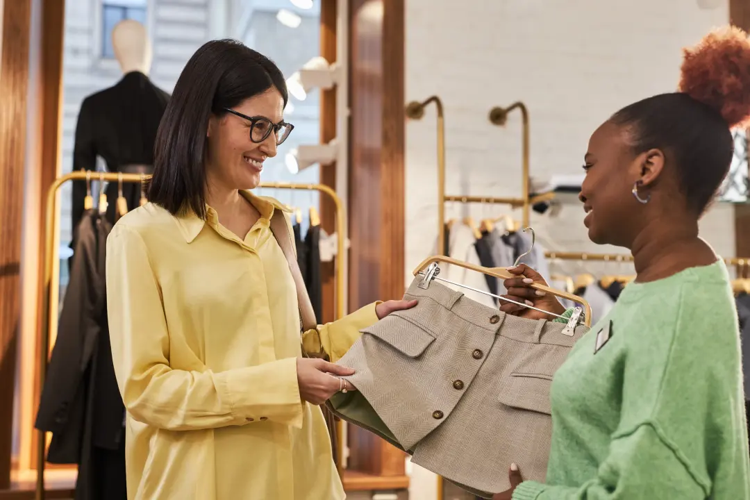 A sales assistant showing a customer a garment in a fashion boutique.