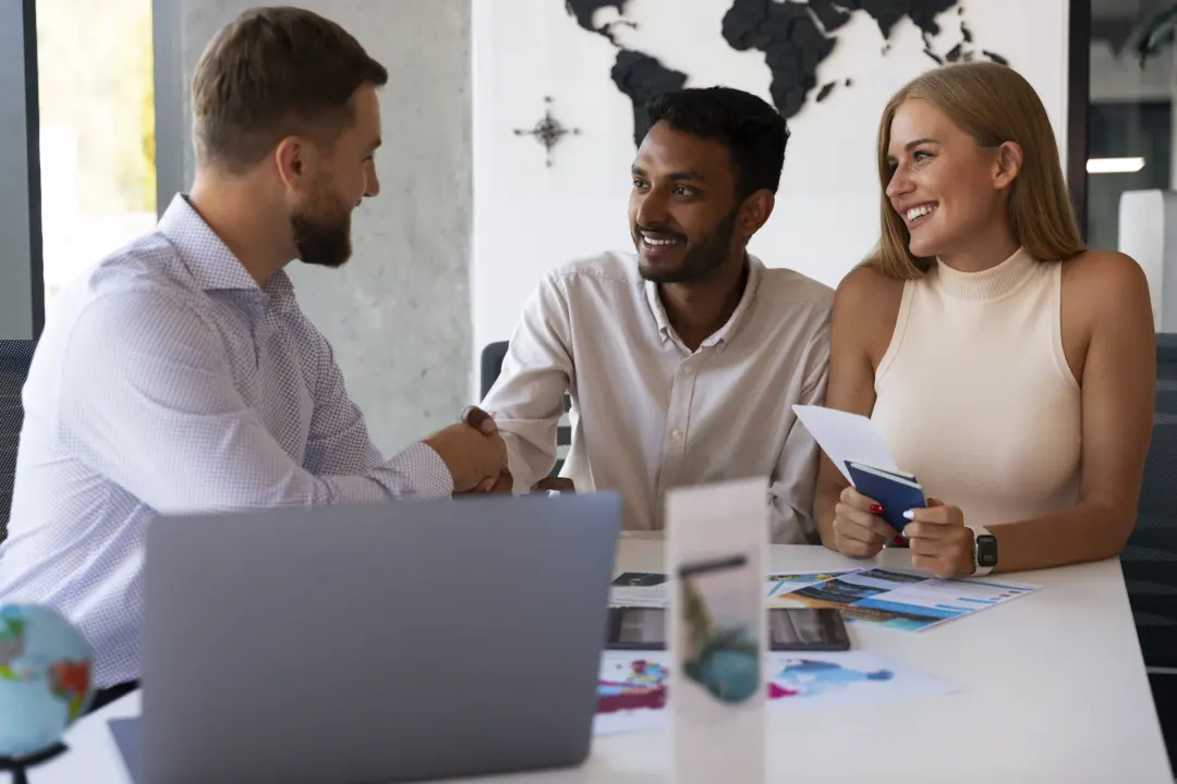 Two clients planning a trip with an agent at a travel agency desk.